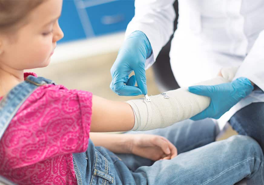 A doctor puts a cast on a girl's arm