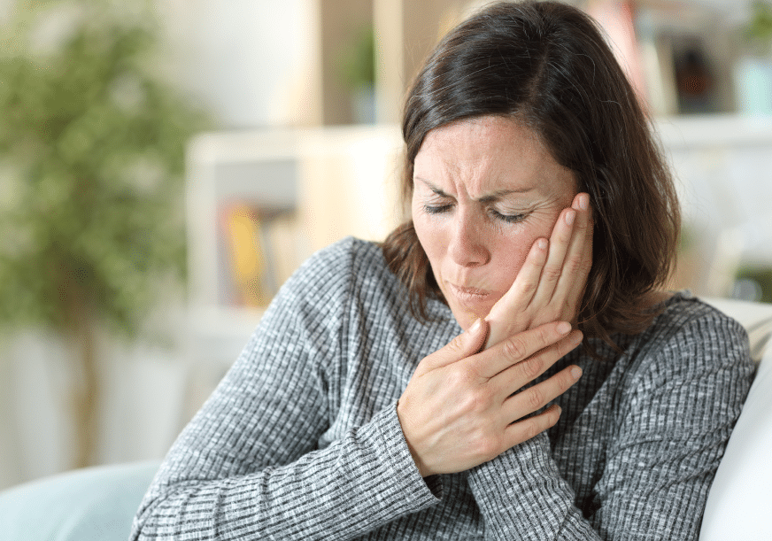 A woman clutches her mouth in pain