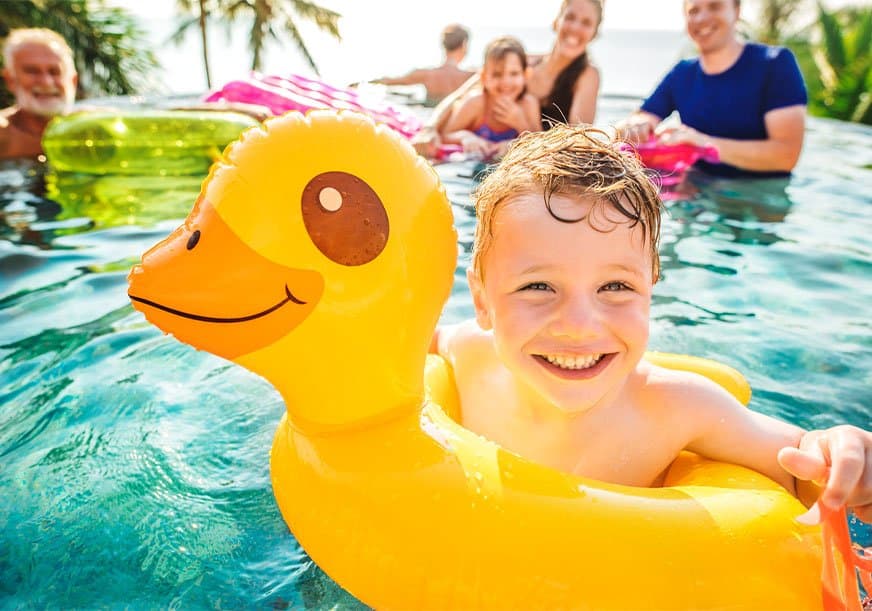 a kid smiles in a pool floatie