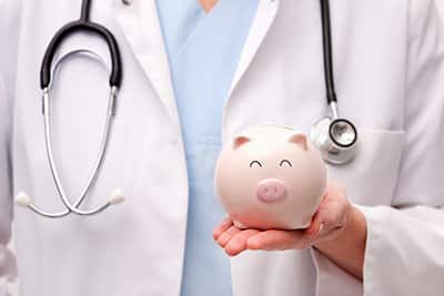 A doctor holds a piggy bank