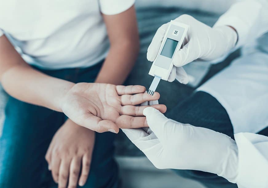 A doctor checks a child's blood sugar level